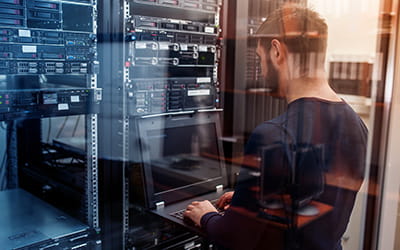 IT professional working on a laptop in a server room