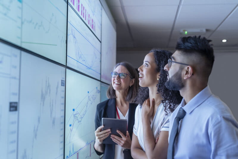 Profesionales de TI analizando datos de negocio en un panel tecnológico empresarial