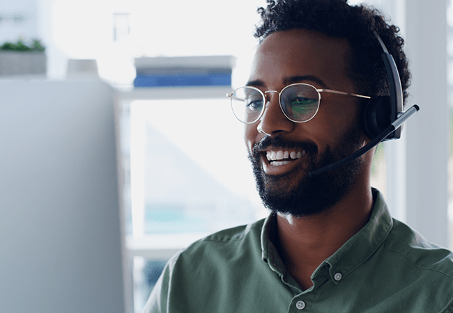 Homme souriant devant un ordinateur pendant qu'il travaille